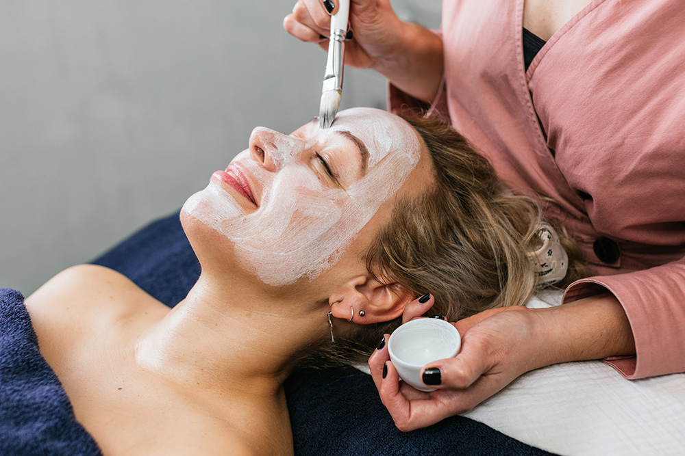 cropped unrecognizable cosmetologist applying moisturizing facial mask face female customer skincare procedure modern beauty salon